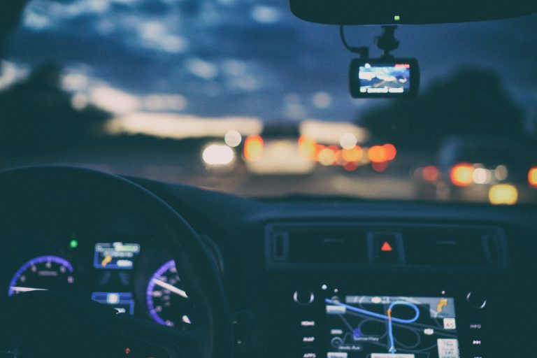 a dashboard of a vehicle with gps directions on screen driving into a dark sunset