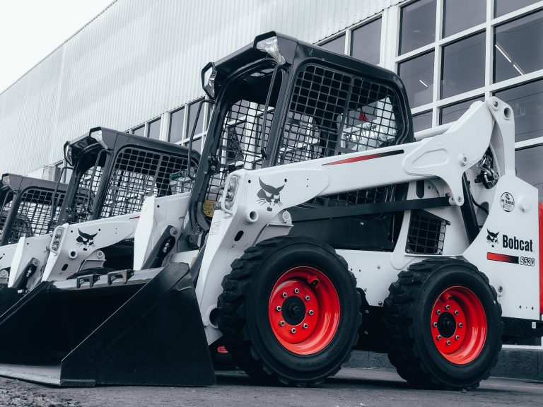 three white bobcats in front of a building